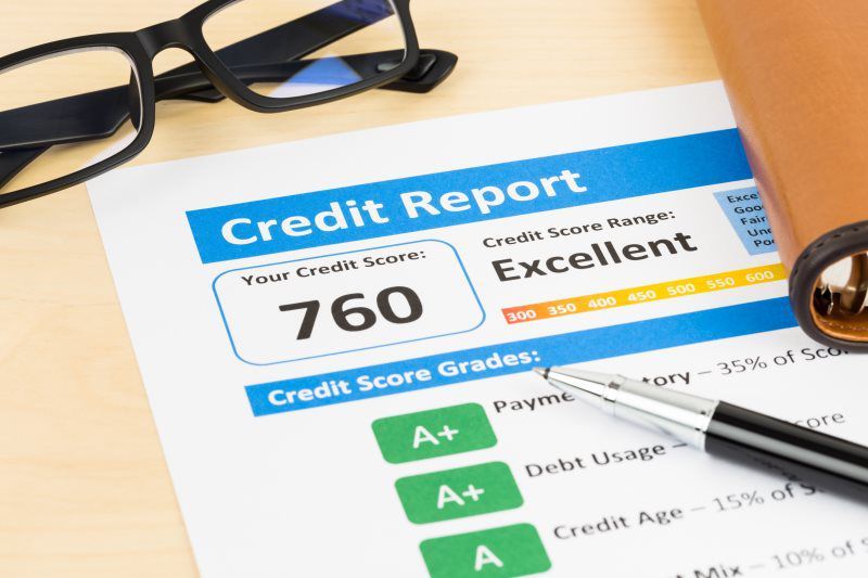 A credit report with a pen and glasses on a table.