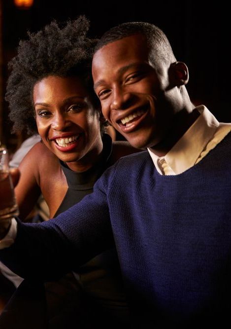 A man and a woman are posing for a picture and smiling for the camera.