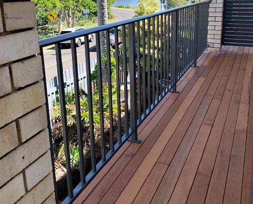 A balcony with a metal railing and a wooden deck