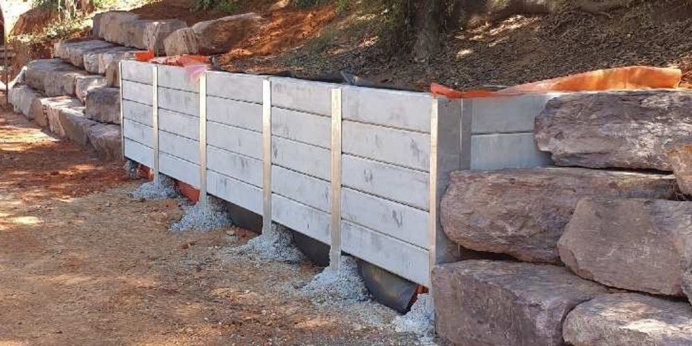 A fence made of wood and metal is surrounded by rocks.