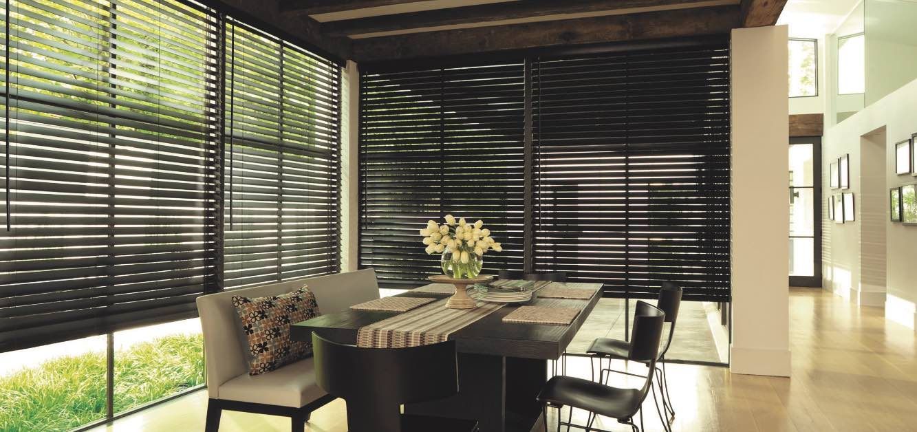 A dining room with a table and chairs and blinds on the windows