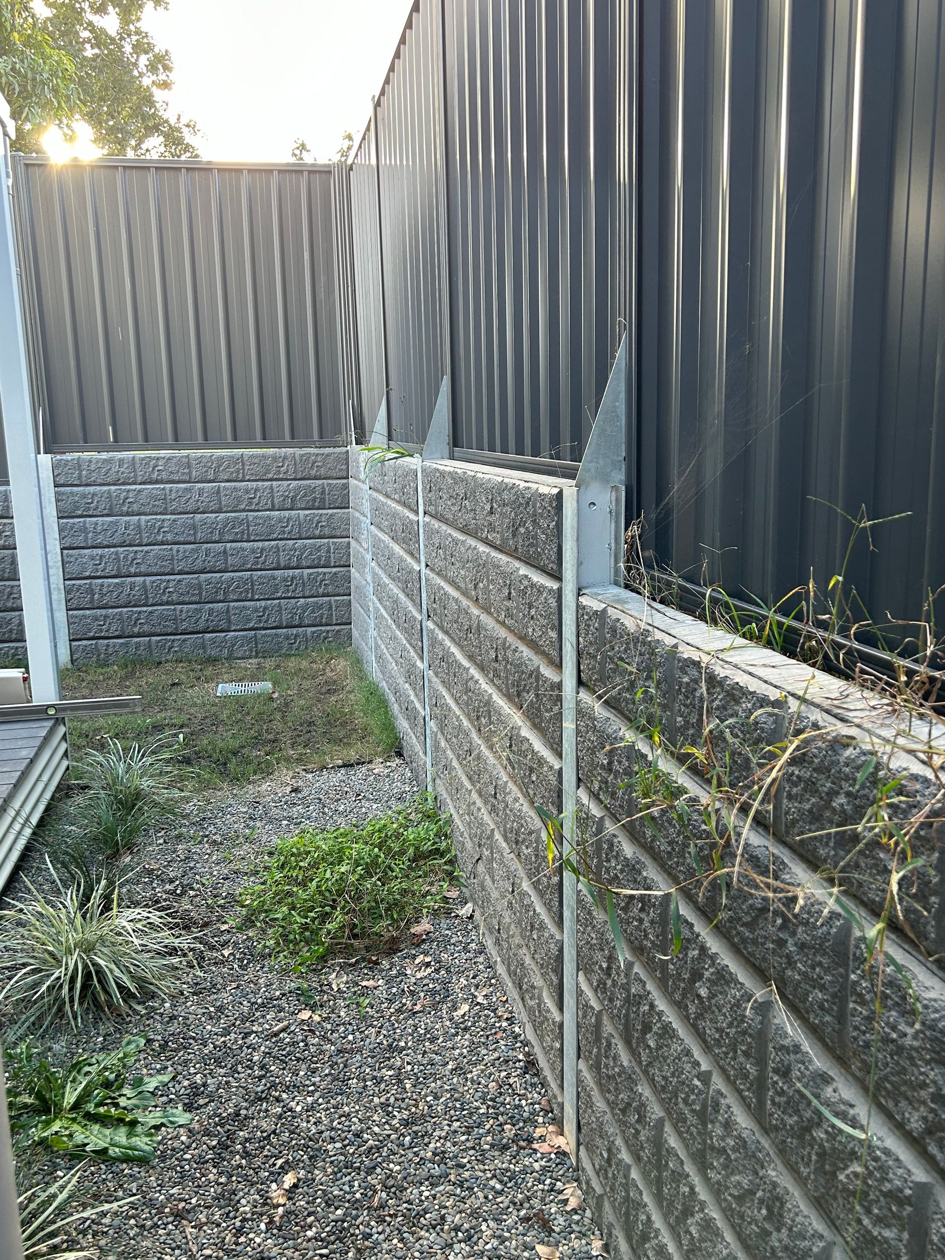 A brick wall with a metal fence in the background.