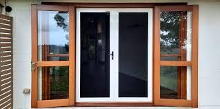 A pair of sliding glass doors with a screen on the side of a house.