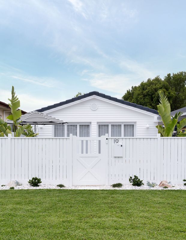 A white house with a white fence in front of it.