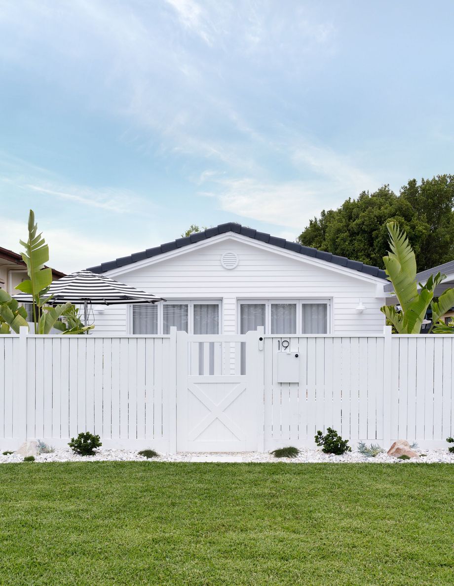 A white house with a white fence in front of it.