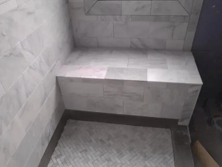 A shower with a bench and a shelf in it.