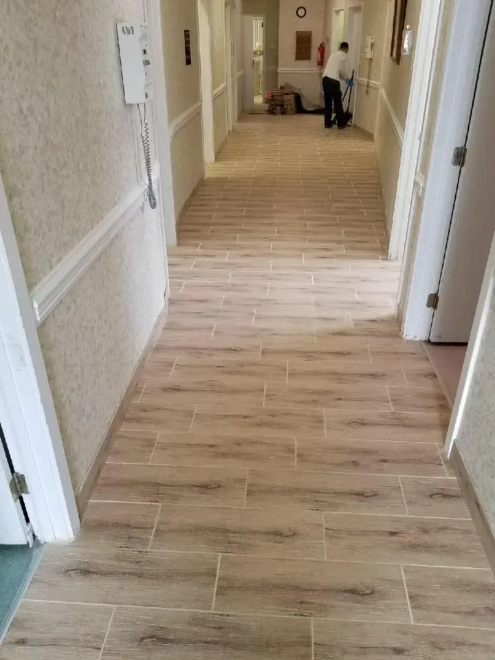 A man is cleaning a hallway with a broom.