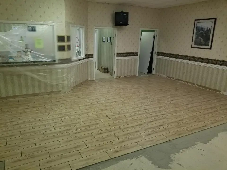 A large room with a wooden floor and a picture on the wall.