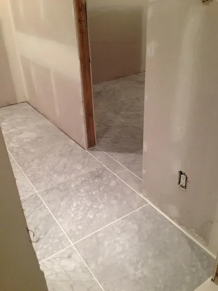 A hallway with tile floors and a door leading to a bathroom.