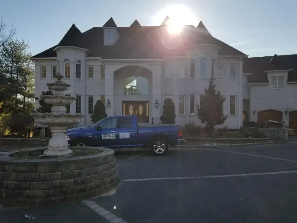 A large white house with a blue truck parked in front of it