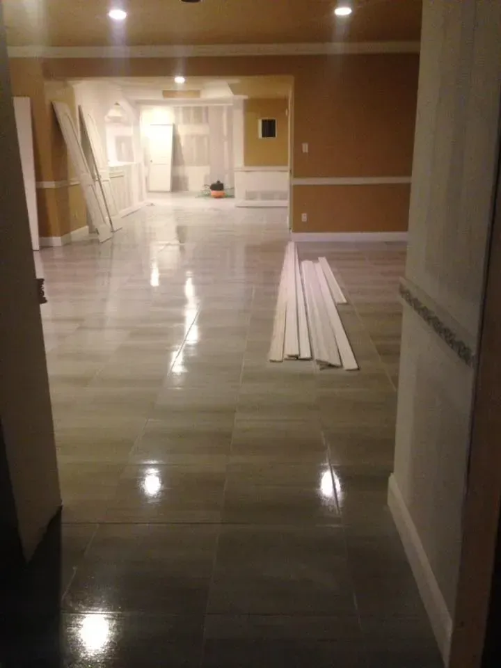 A large empty room with a wooden floor and a stack of wooden boards on the floor.