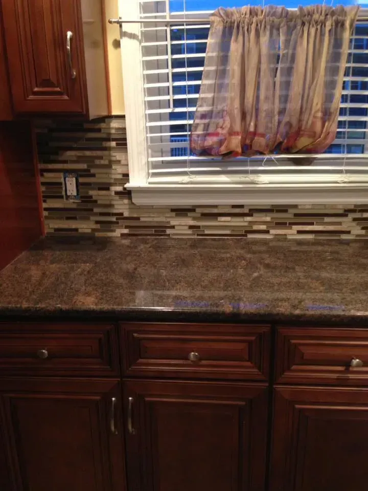 A kitchen counter with a window and a curtain on it.