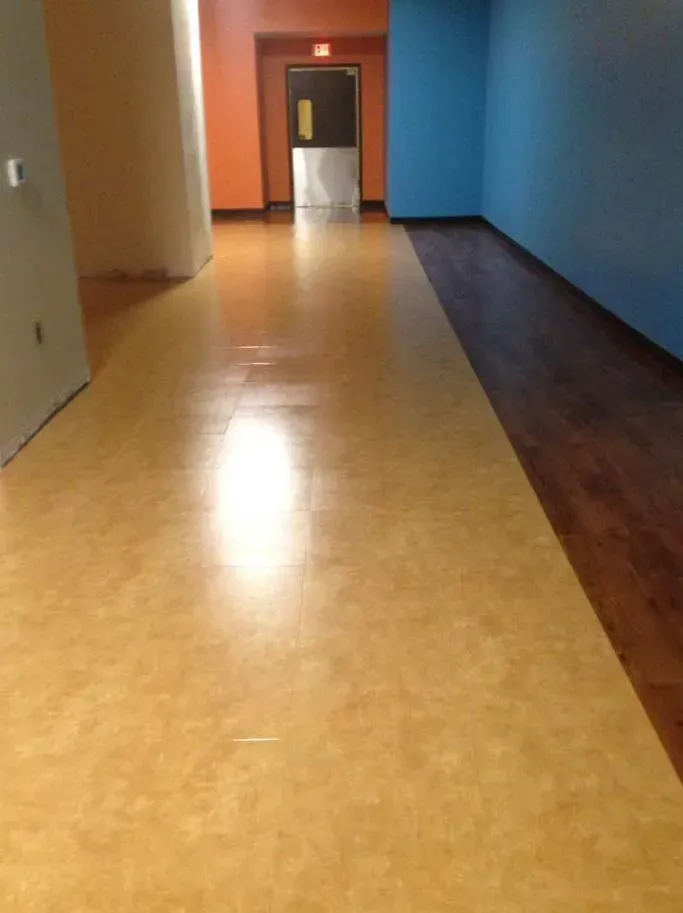 A hallway with a wooden floor and a blue wall.
