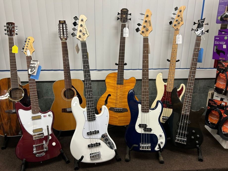 Guitars and bass guitars on display. Electric, acoustic, and bass guitars with various colors and designs.