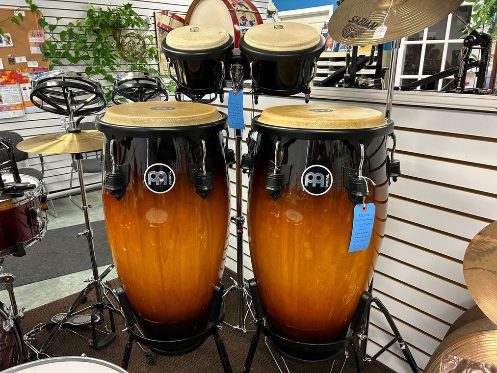 Two conga drums with a black and amber finish, displayed in a music store.