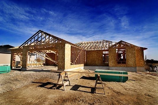 A house is being built in the middle of a dirt field.