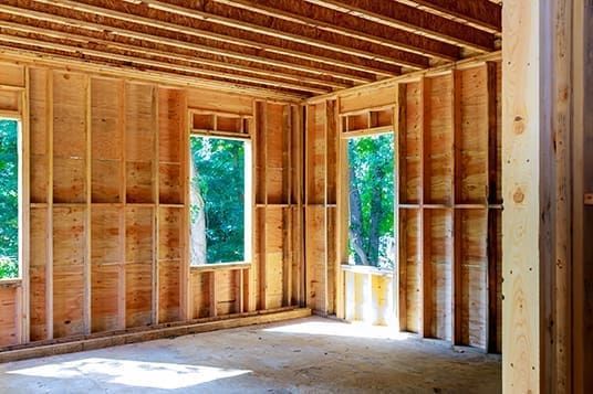 A room in a house under construction with wooden walls and windows.
