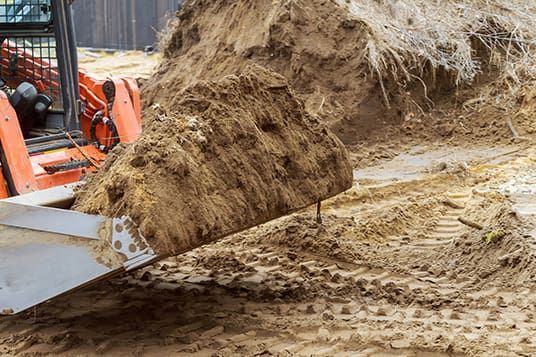 A bulldozer is loading dirt into a bucket on a construction site.