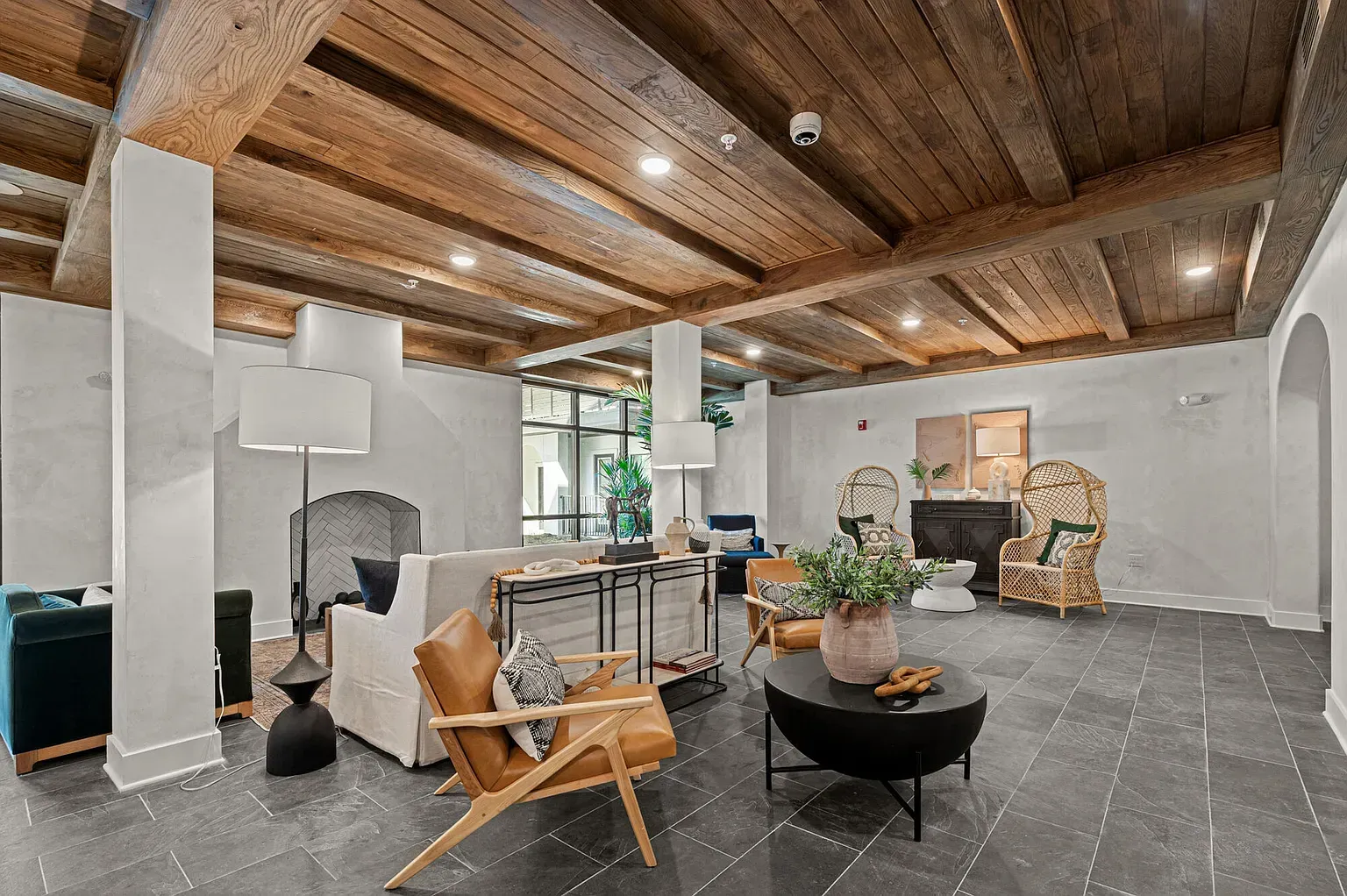 Interior community lounge with wood-beam ceiling, tile floor, and comfortable seating.