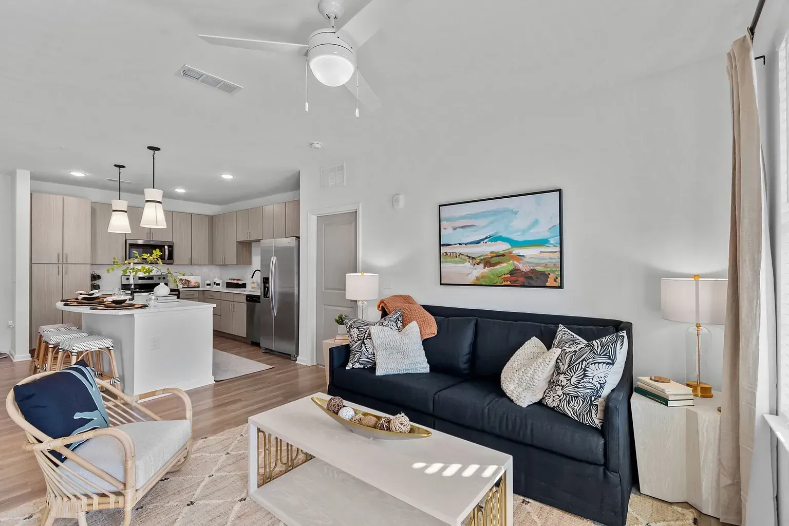 Open-concept living area with navy sofa, white coffee table, and a kitchen island with pendant lights.