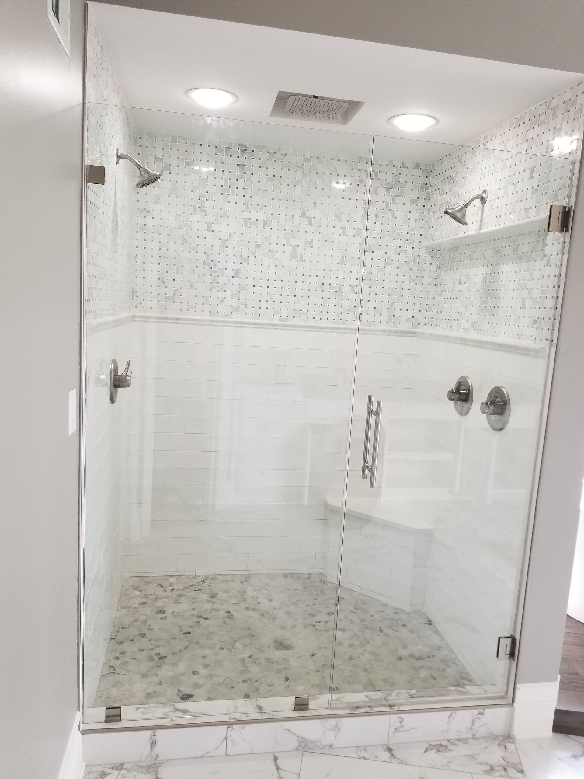 A bathroom with a walk in shower with a glass door.