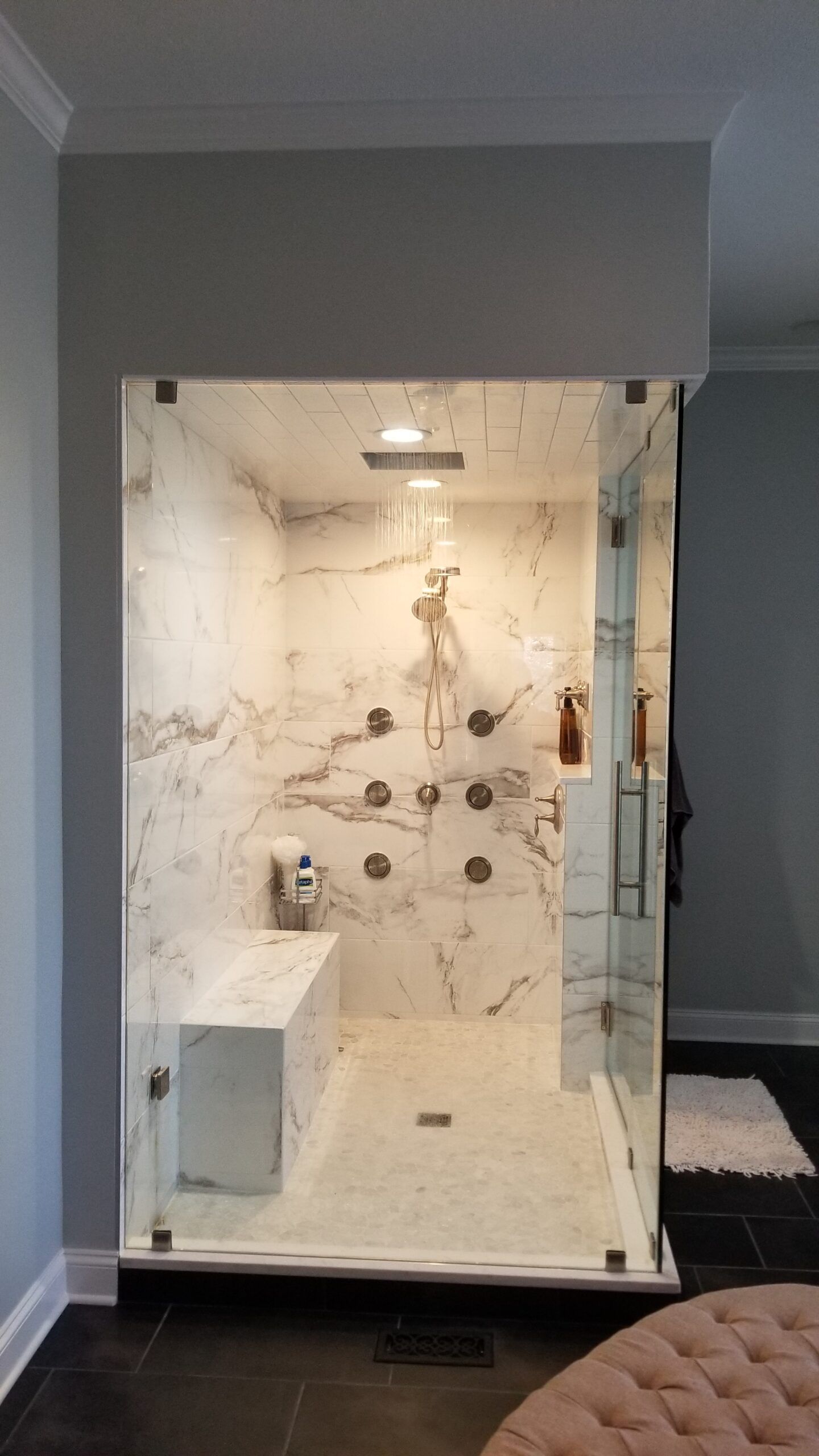 A bathroom with a walk in shower and a bench.