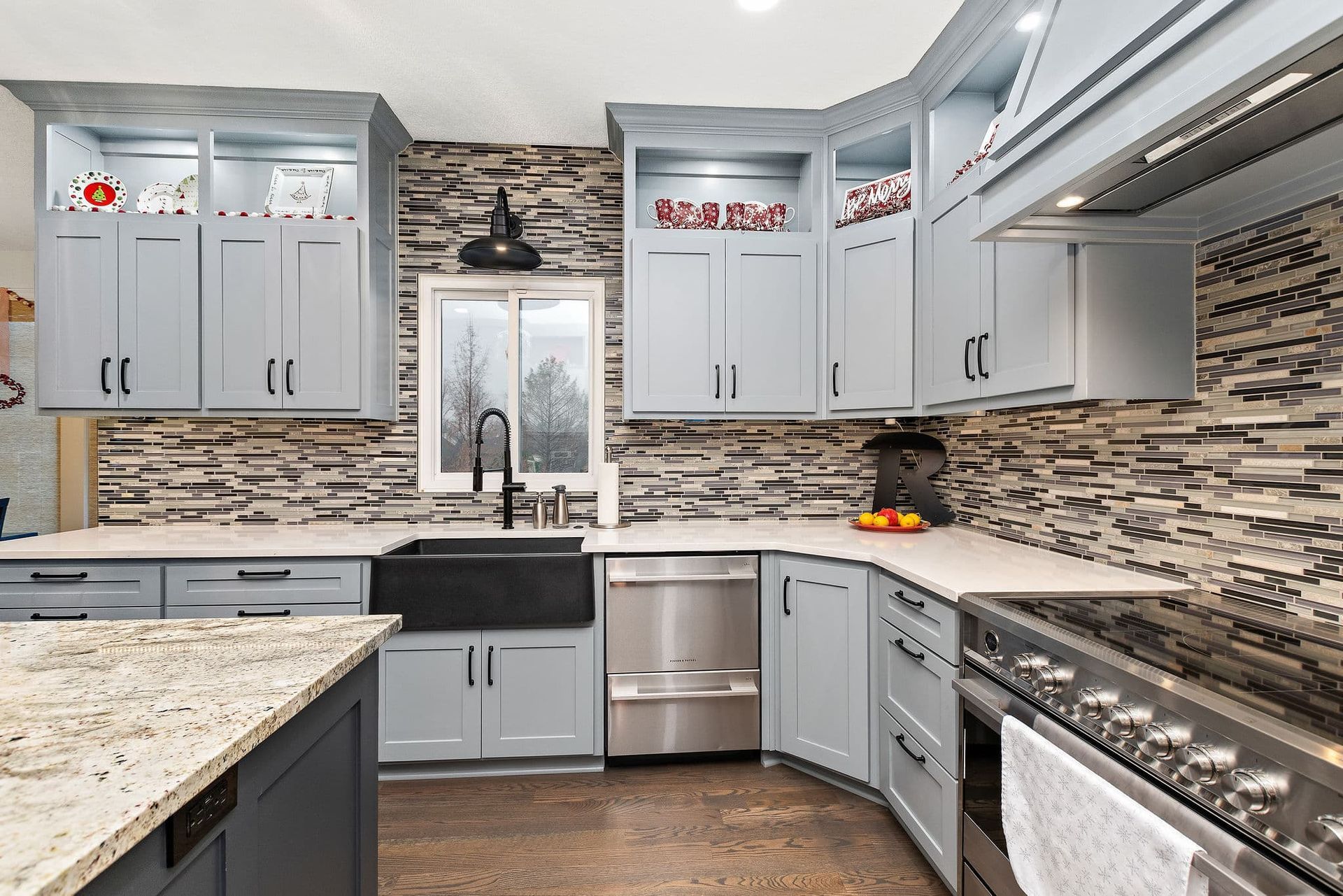A kitchen with blue cabinets , granite counter tops , stainless steel appliances , a sink and a stove.