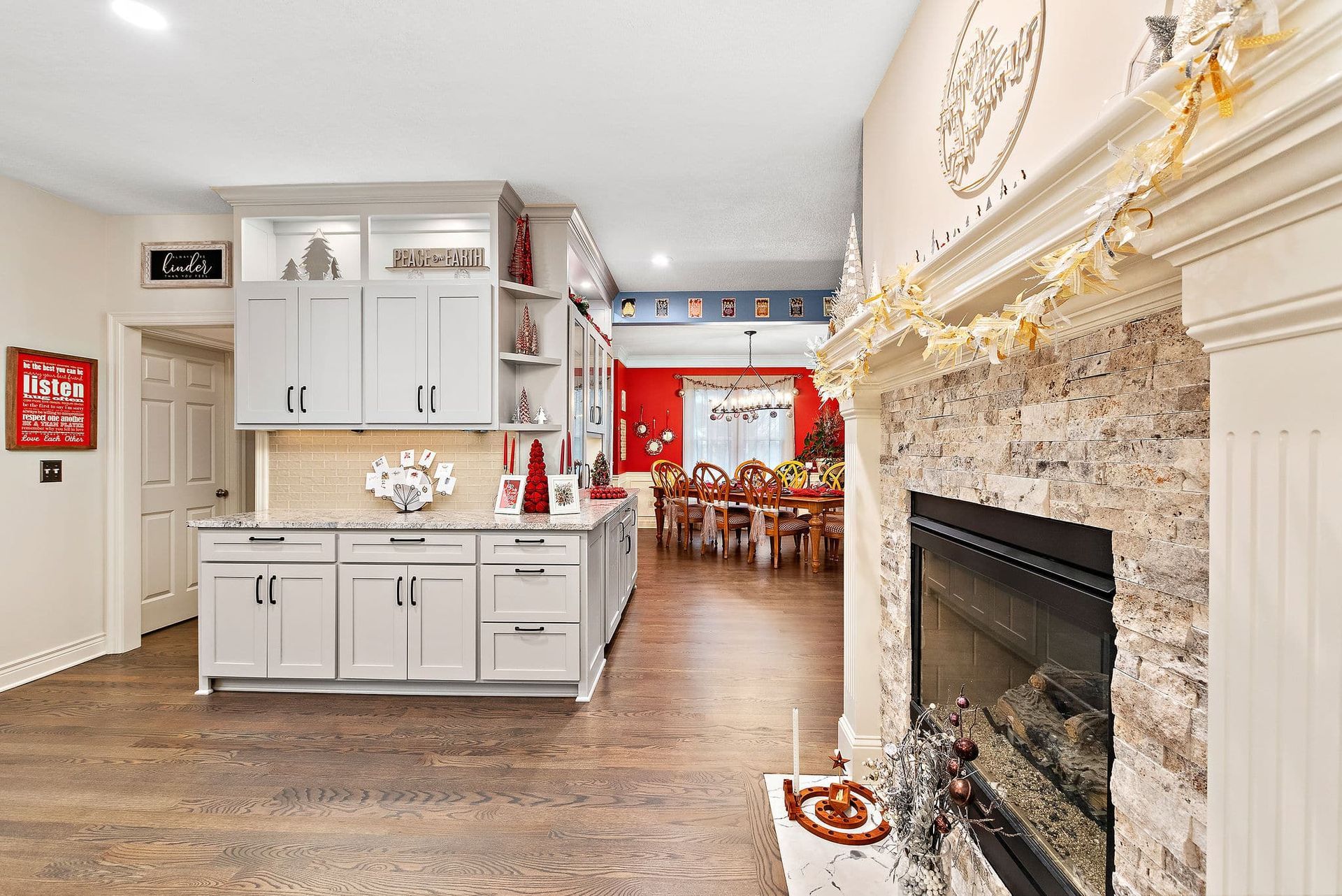 A kitchen with a fireplace and a dining room in the background.