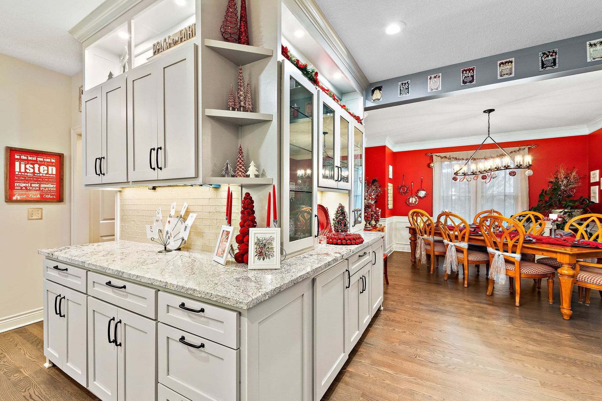 A kitchen with white cabinets and granite counter tops is decorated for christmas.