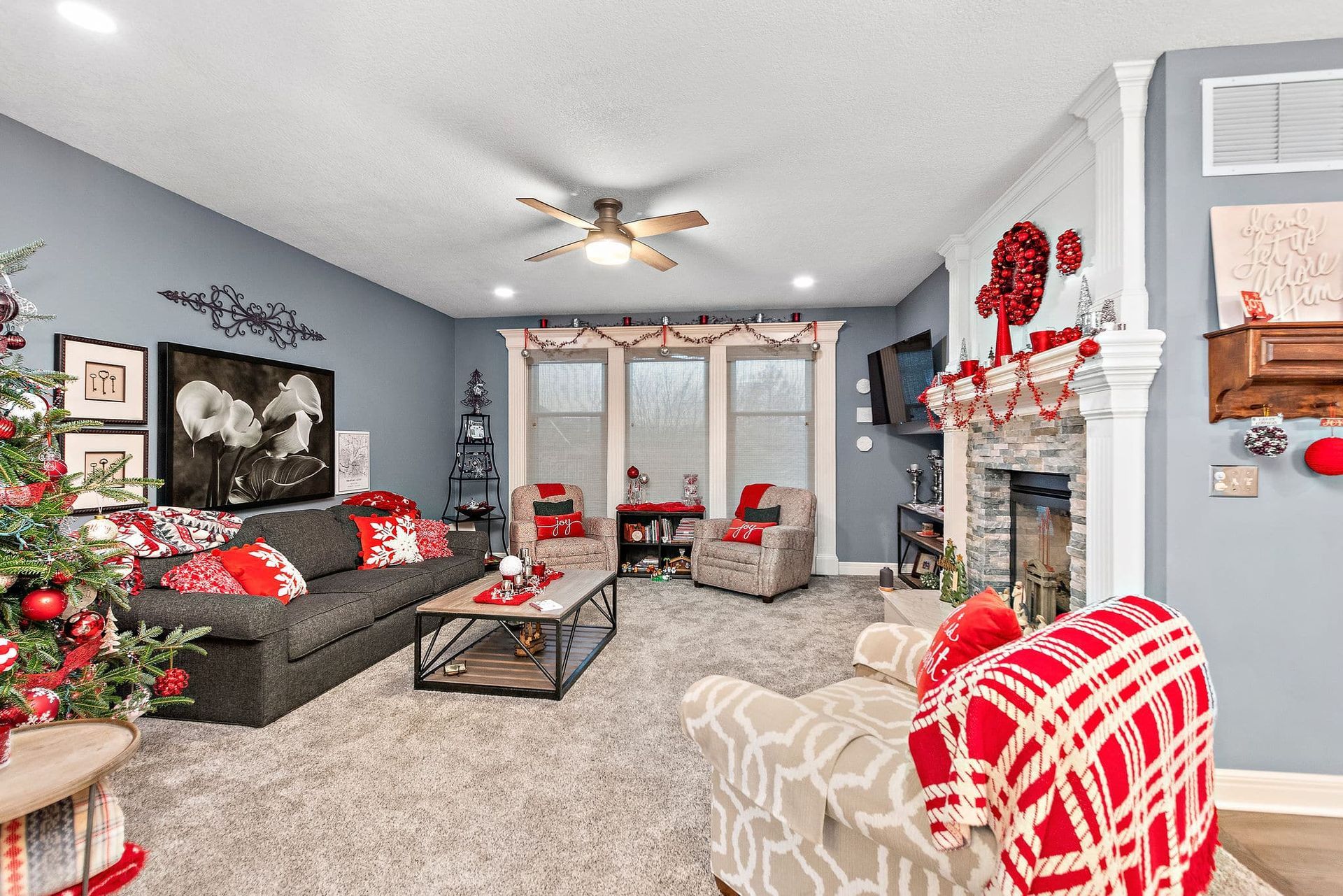 A living room decorated for christmas with a couch , chairs , coffee table and fireplace.