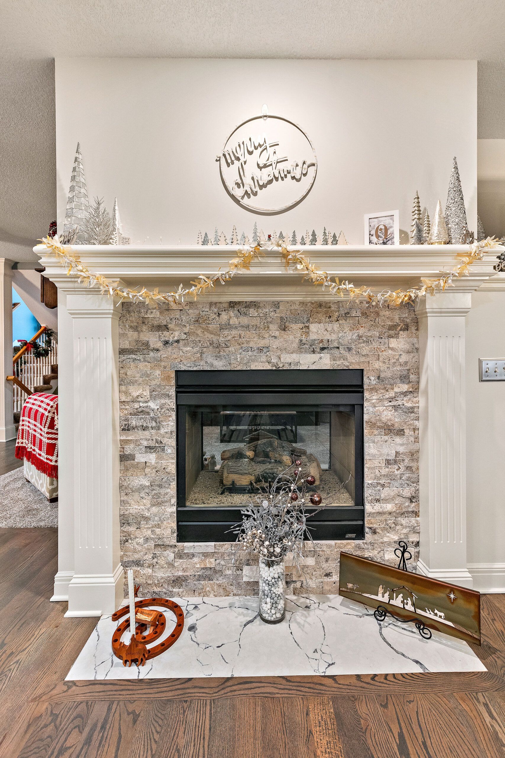 A living room with a fireplace and a mantle decorated for christmas.