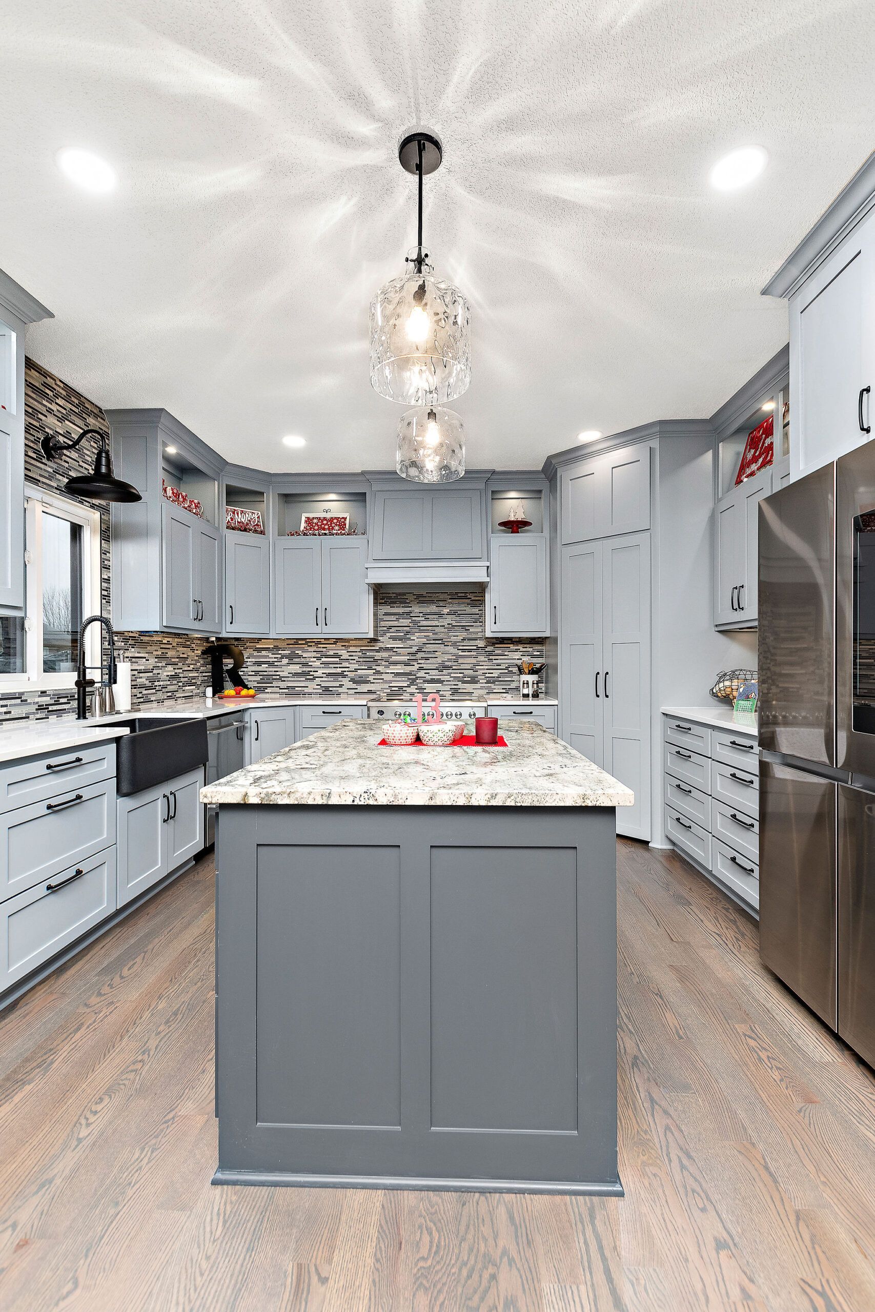A kitchen with white cabinets and stainless steel appliances and a large island in the middle.