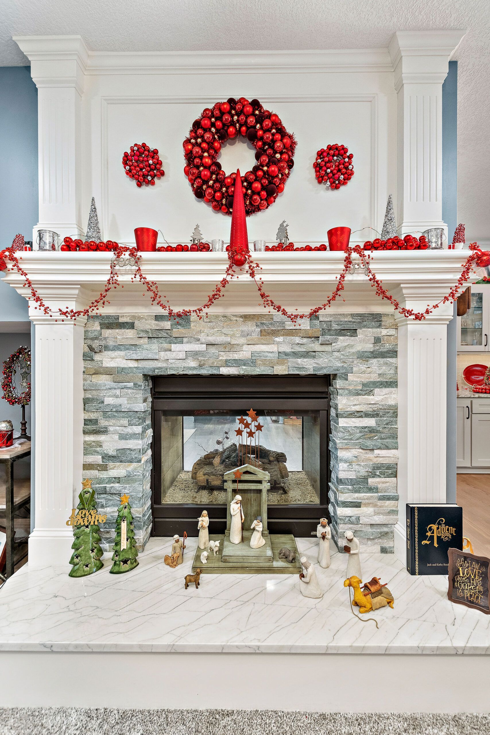 A fireplace is decorated for christmas with a wreath and candles.