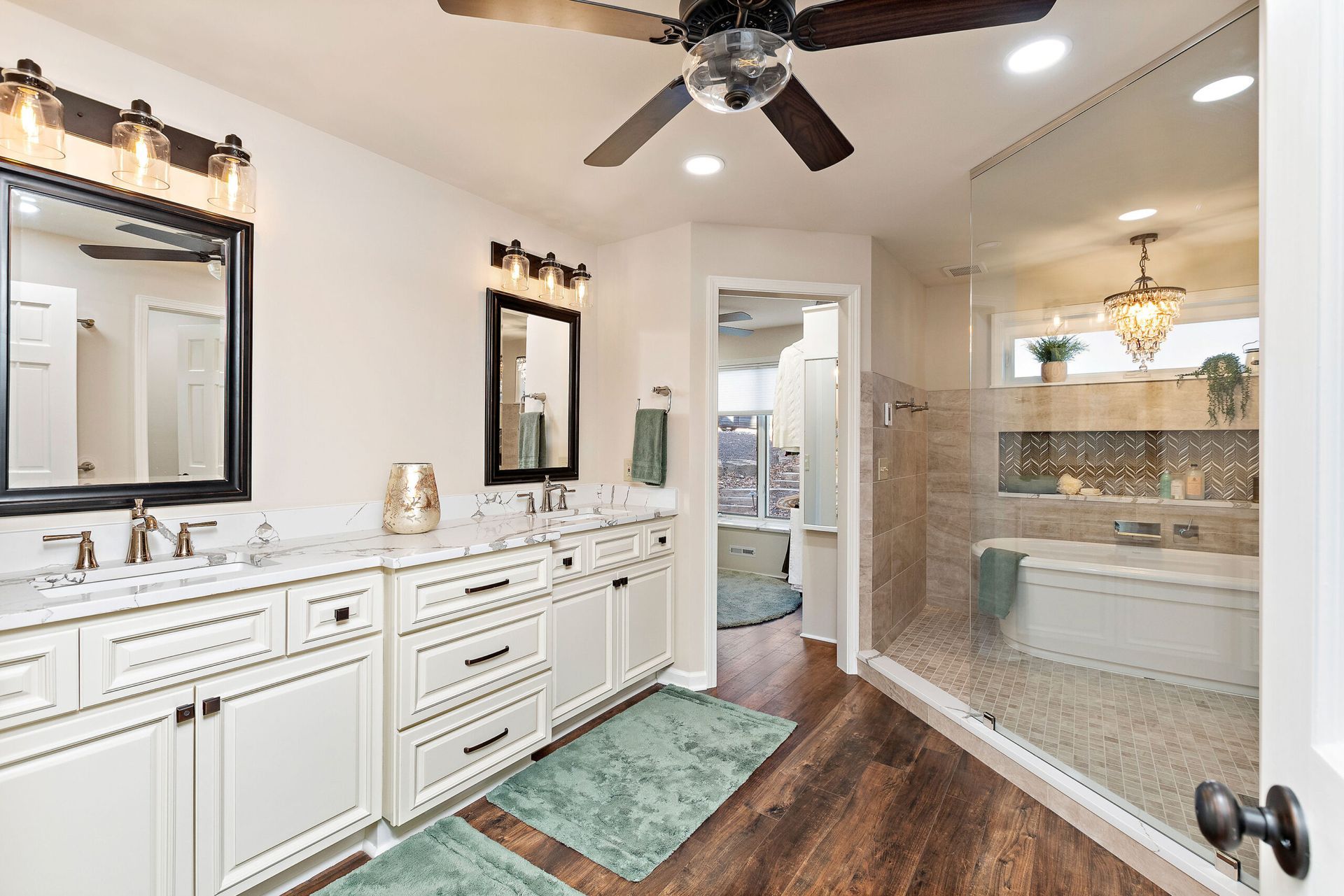 A bathroom with two sinks , a ceiling fan , and a walk in shower.