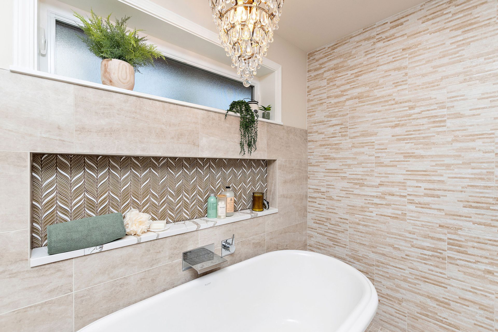 There is a bathtub in the bathroom with a chandelier hanging from the ceiling.