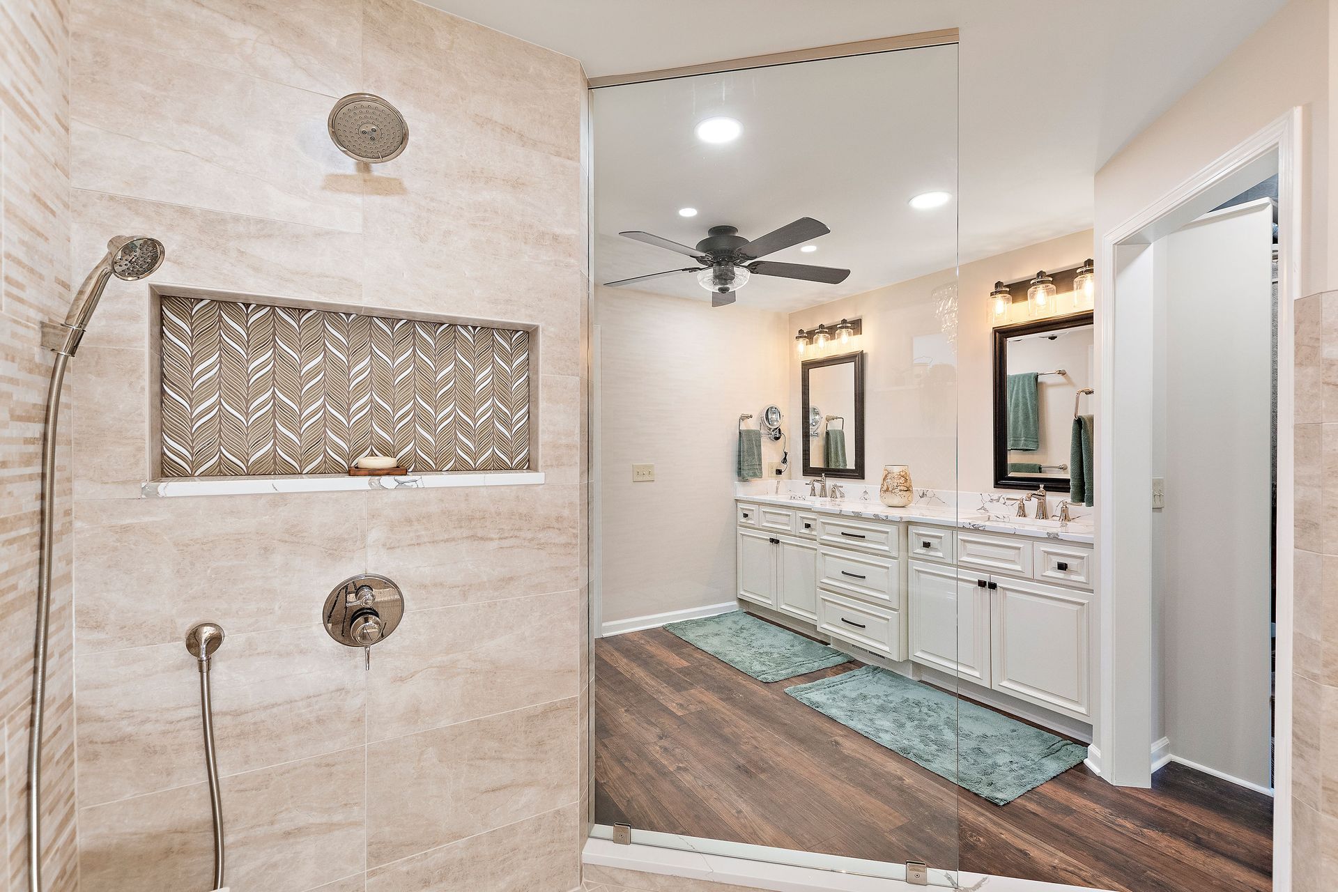 A bathroom with a walk in shower and a ceiling fan.