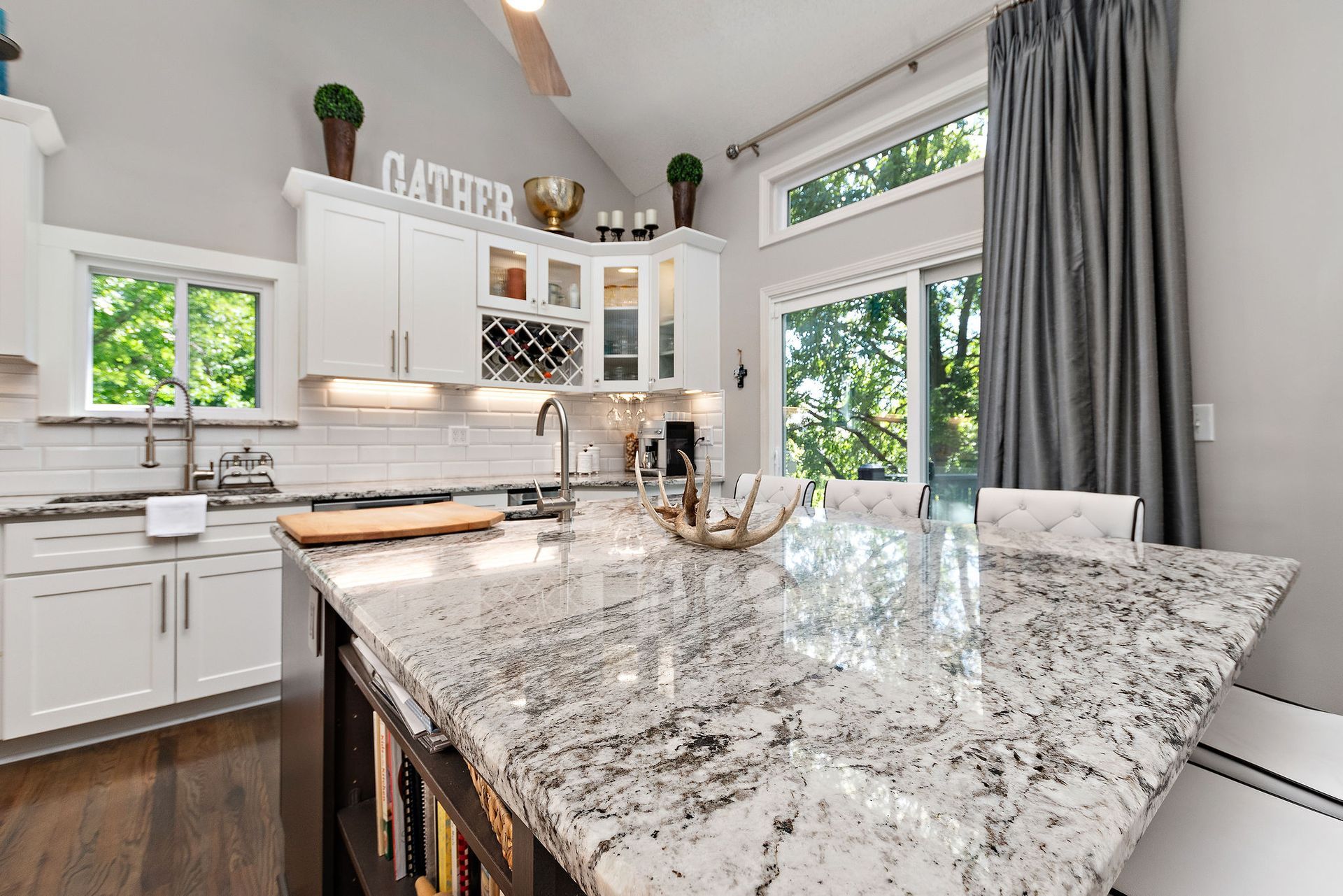 A kitchen with granite counter tops and white cabinets.