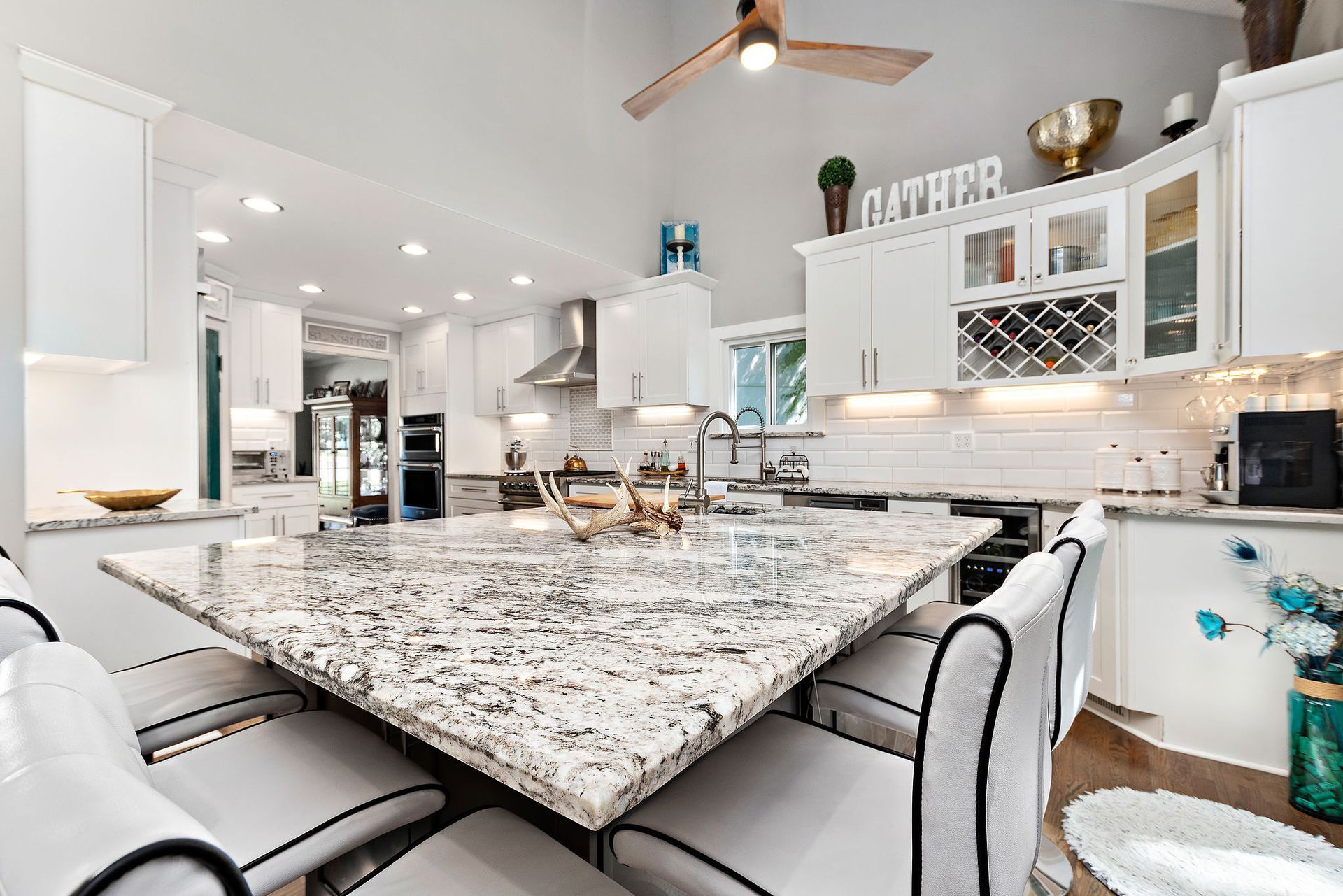 A kitchen with a large granite counter top and white cabinets.