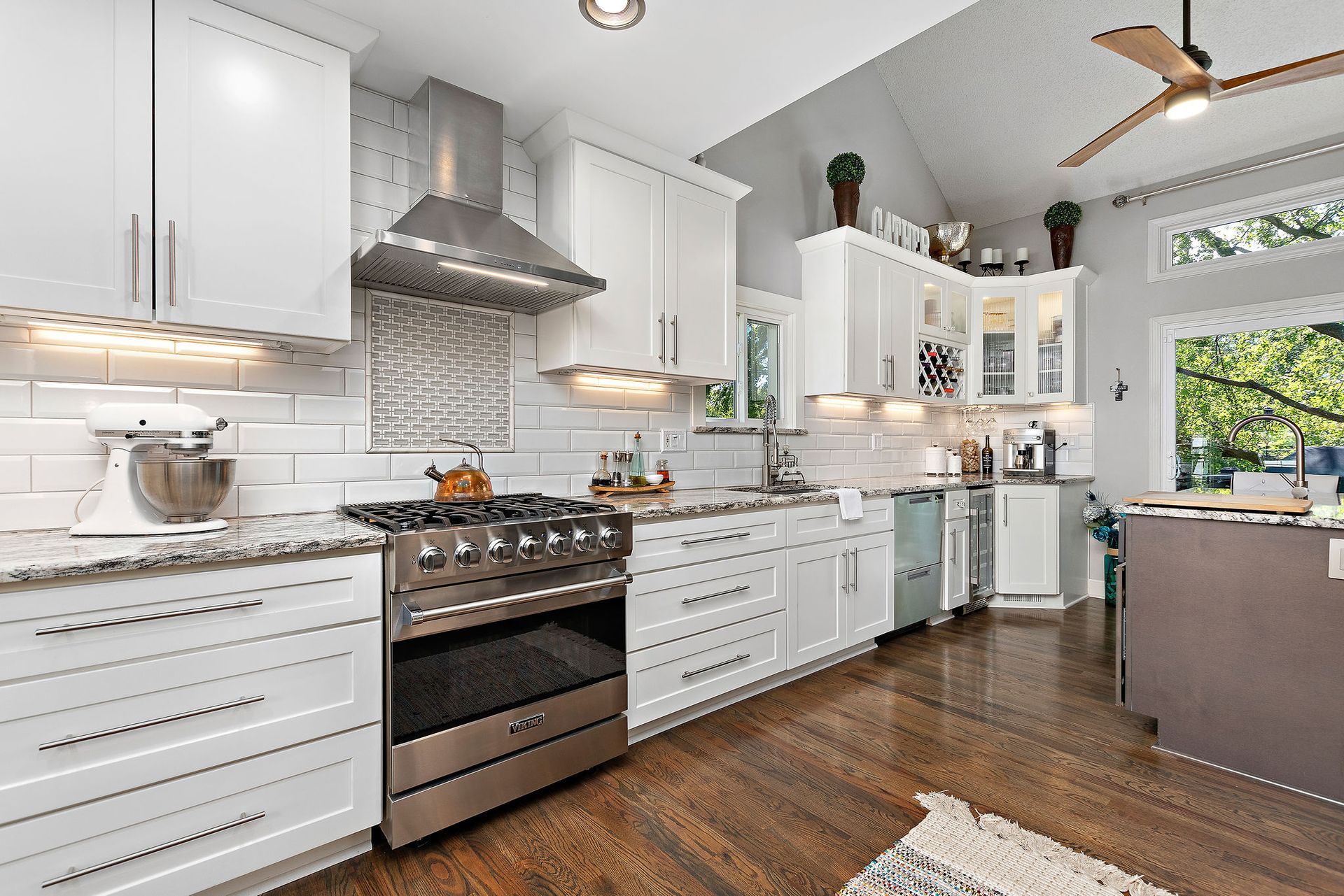 A kitchen with white cabinets and stainless steel appliances and a ceiling fan.