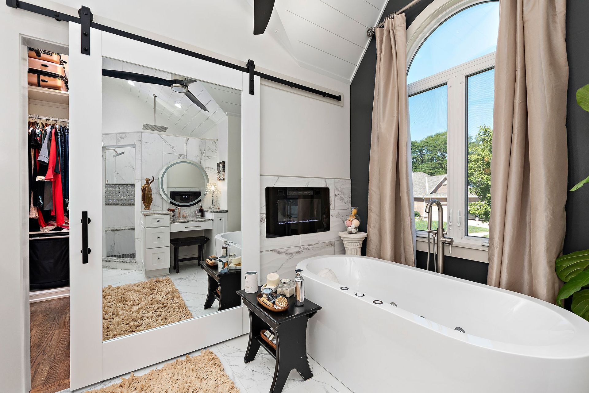 A bathroom with a bathtub , mirror and sliding barn doors.
