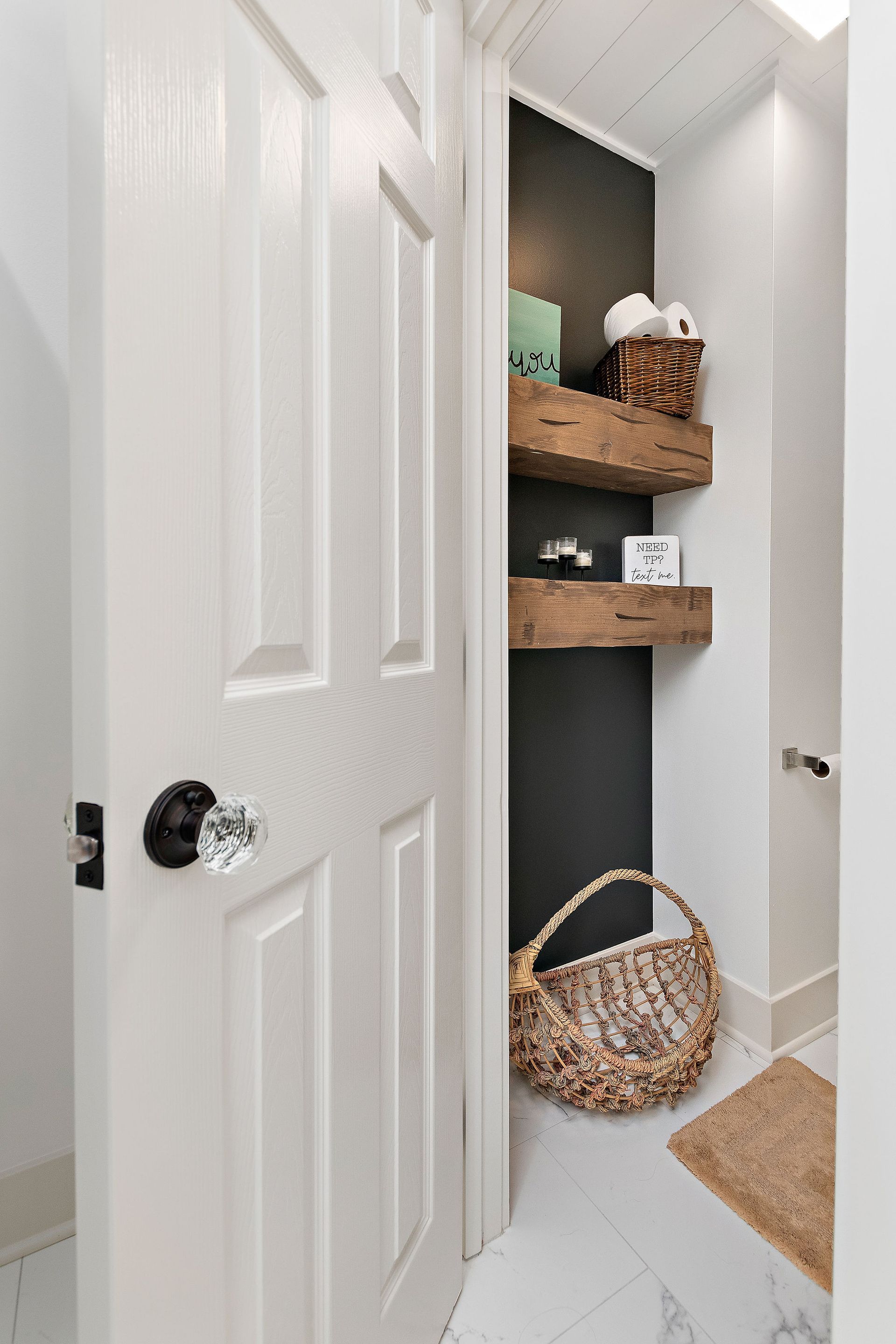 A bathroom with a white door and wooden shelves.