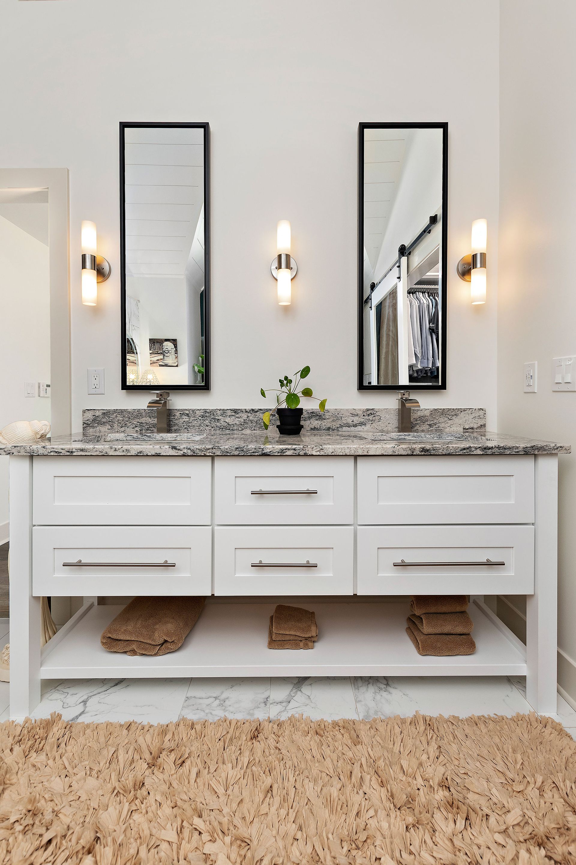 A bathroom with two sinks , two mirrors and a rug.