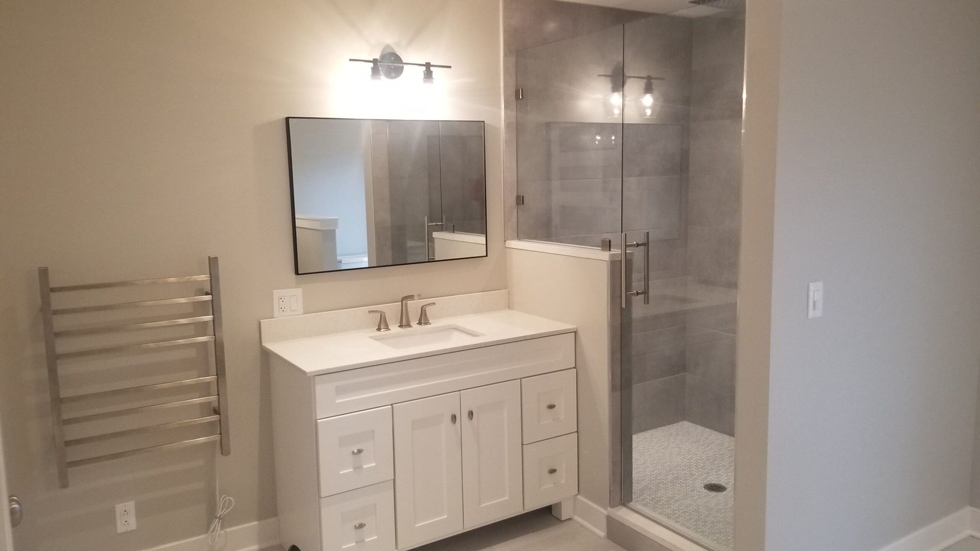A bathroom with a sink , mirror , and walk in shower.