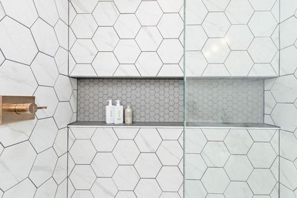 A bathroom with white hexagon tiles and a shower stall.