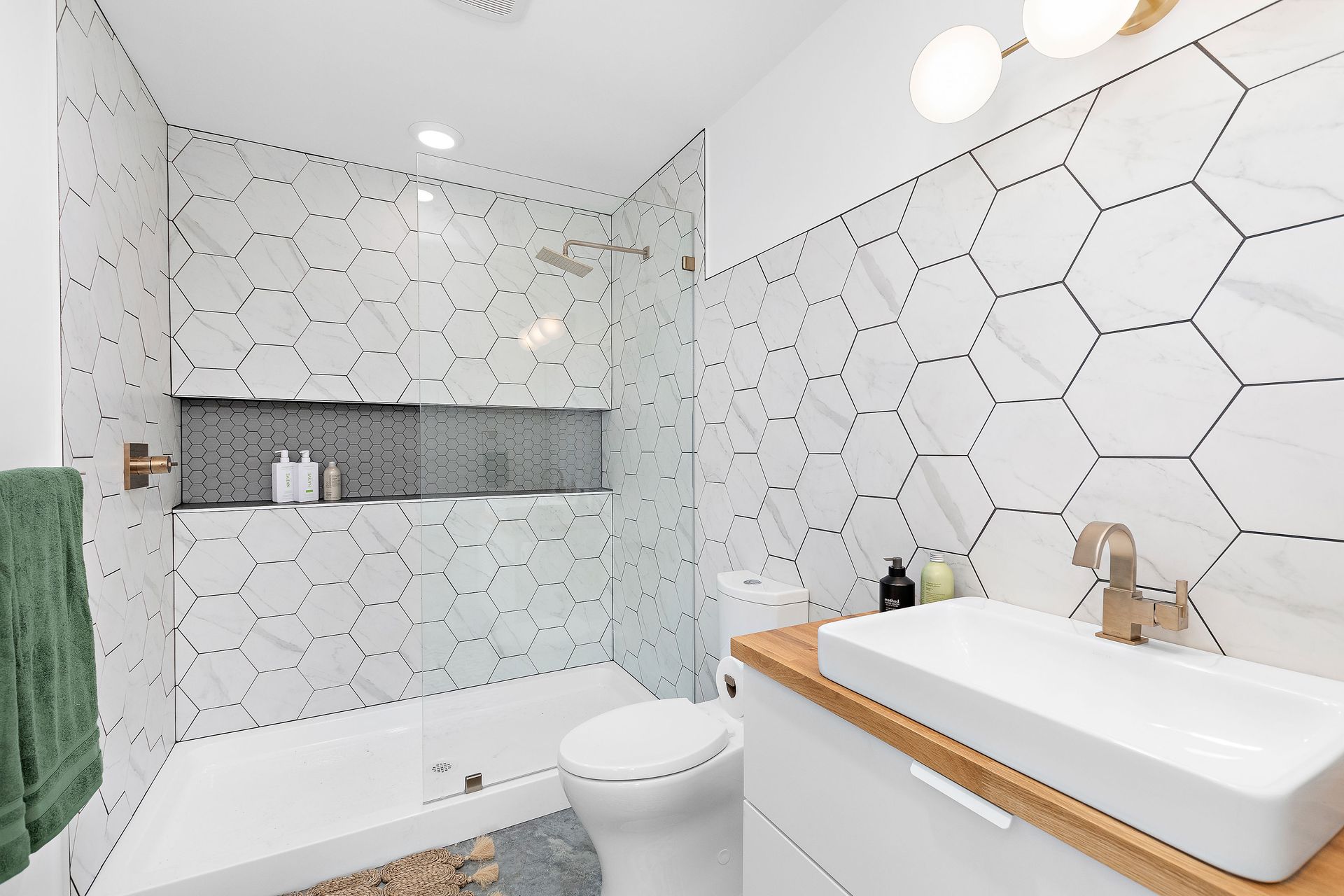 A bathroom with white tiles , a toilet , sink and shower.