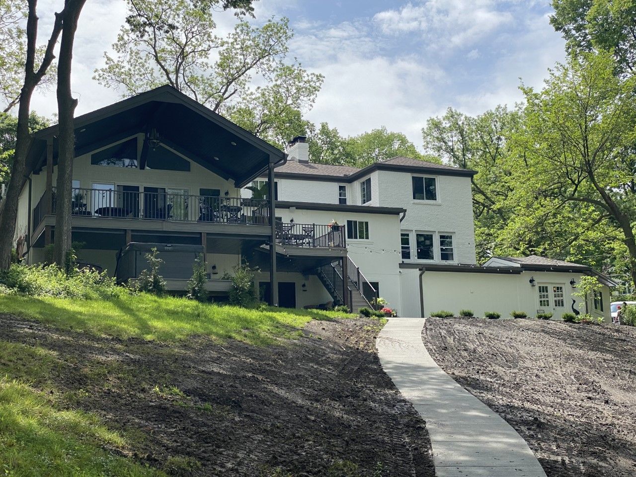 A large white house with a walkway leading to it is surrounded by trees.