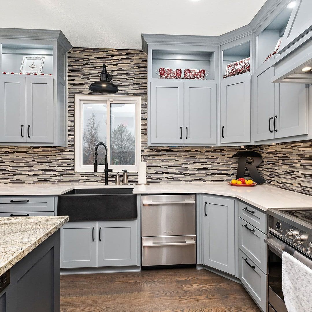 A kitchen with gray cabinets , stainless steel appliances , a sink , and a window.