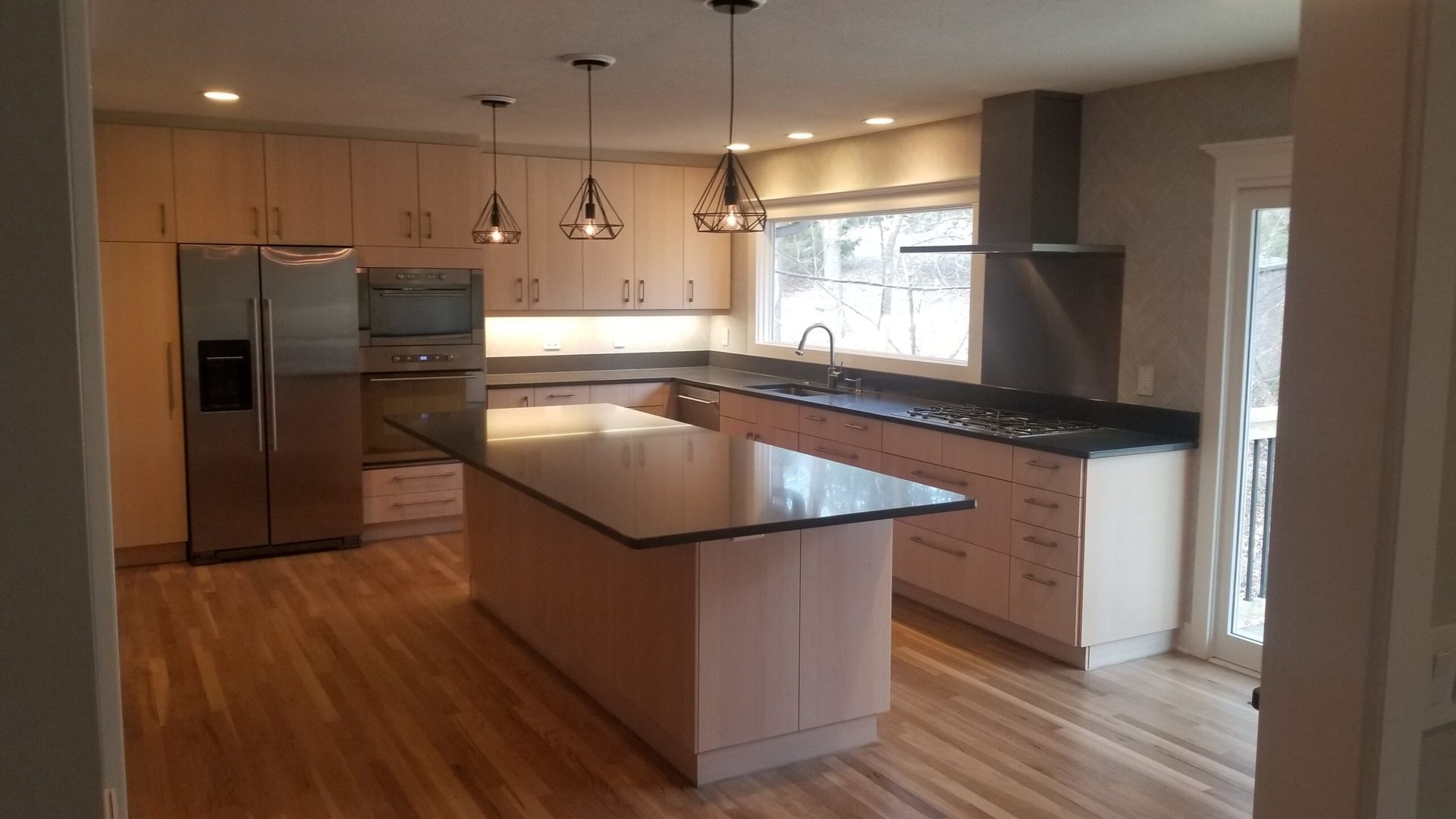 A kitchen with stainless steel appliances and a large island in the middle.