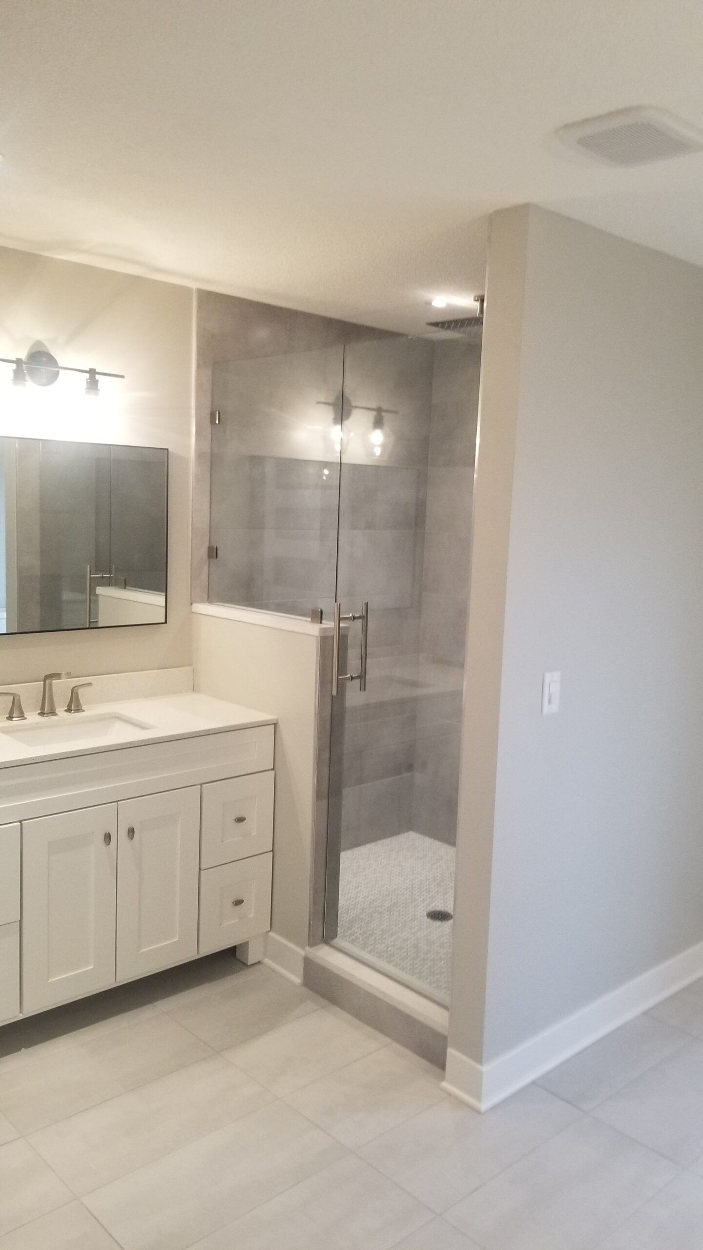 A bathroom with two sinks and a walk in shower.