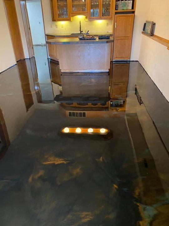 Metallic epoxy floor in a kitchen with wooden cabinets. Reflections of the room are visible.